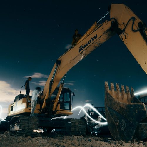pexels-photo-2449603-2449603 A powerful excavator at a construction site under the night sky, with workers around.